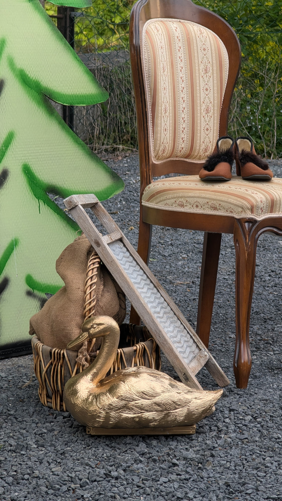 Antiker Stuhl mit gestreifter Polsterung, daneben goldene Gans, Leiter und Tannenbaum