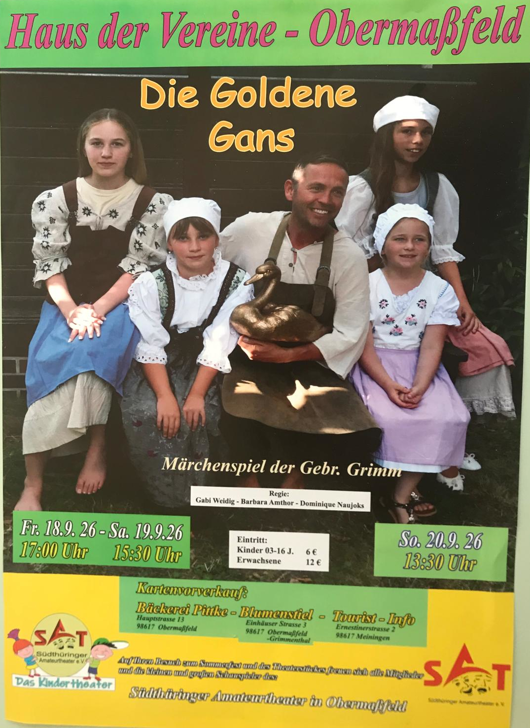 Familie posiert vor schwarzer Bühne mit goldener Figur, Kinder im Trachtenlook, Plakattext „Die Goldenen Gans“.